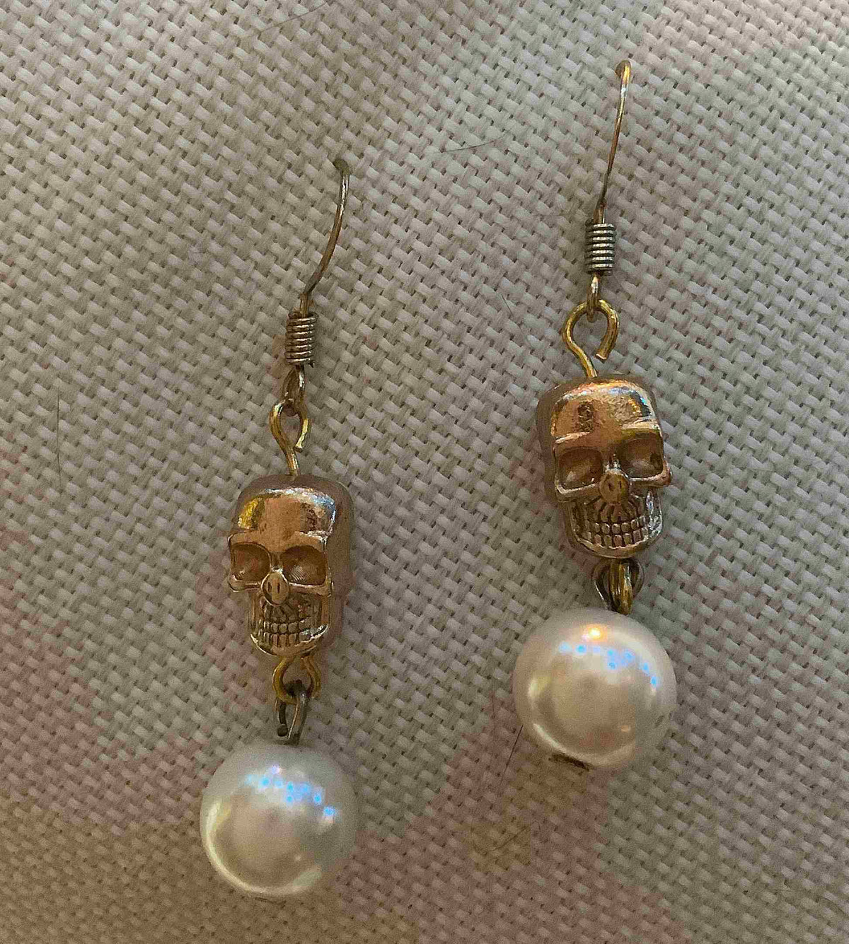 a pair of earrings with a skull and a pearl.