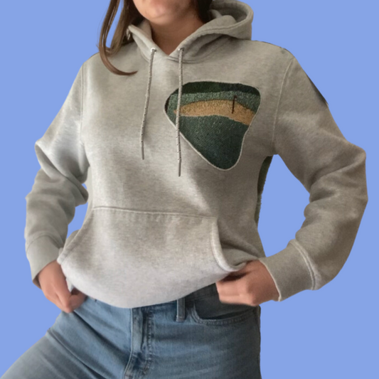 A woman wearing a grey hoodie and jeans.