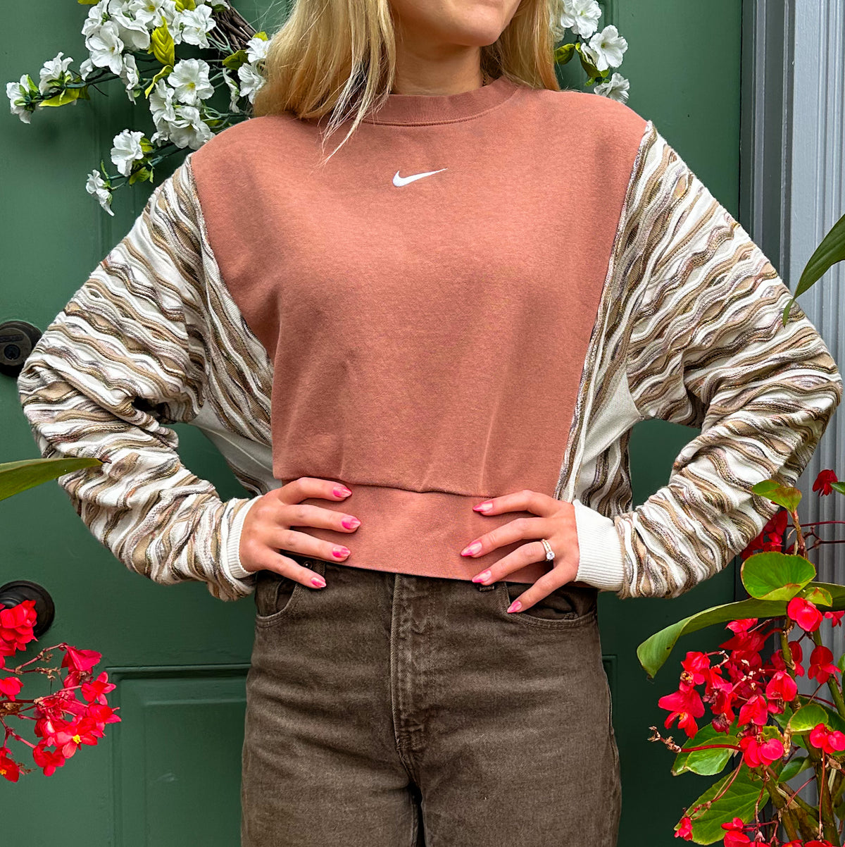 A woman wearing a nike cropped sweater and brown pants.