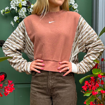 A woman wearing a nike cropped sweater and brown pants.