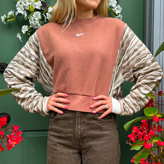 A woman wearing a nike cropped sweater and brown pants.