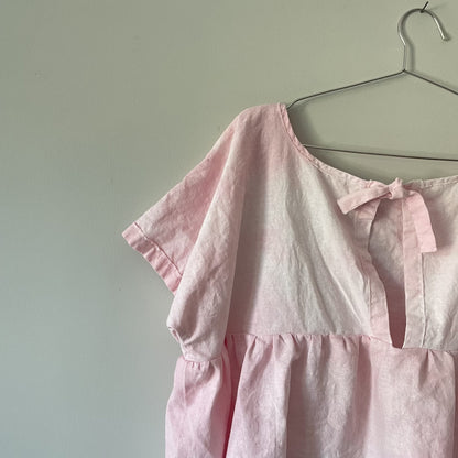 A pink blouse hanging on a hanger.