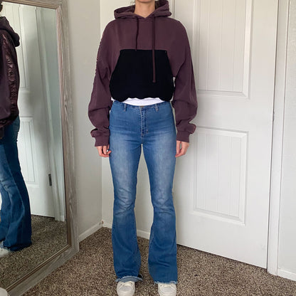 A woman wearing a purple hoodie and flared jeans.