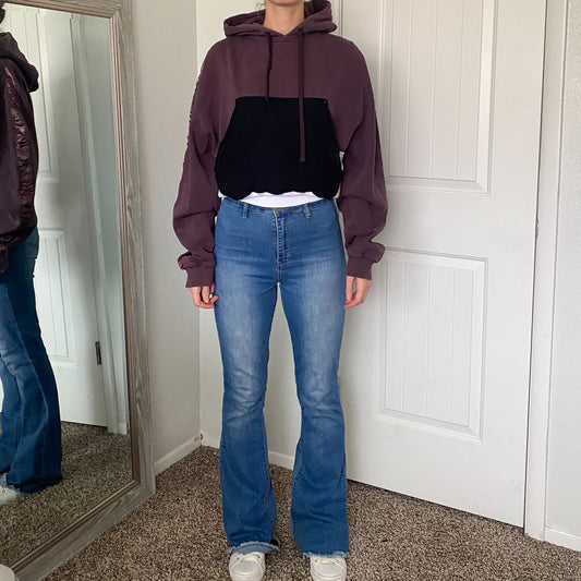 A woman wearing a purple hoodie and flared jeans.