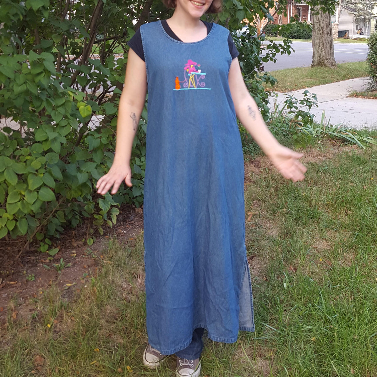 A woman wearing an Embroidered Dark Wash Kangaroo Pocket Mini Skirt standing in the grass.