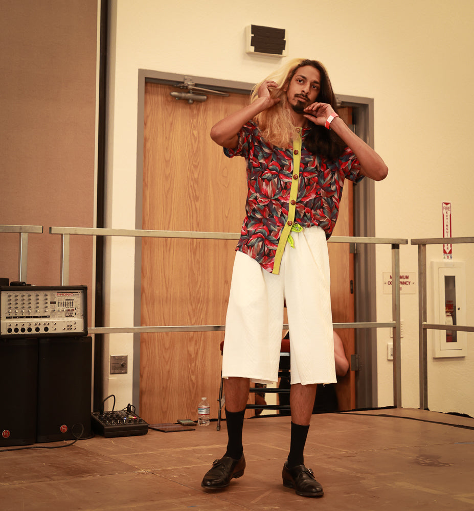 A man wearing a Men's Floral Shirt and long hair standing in front of a door.