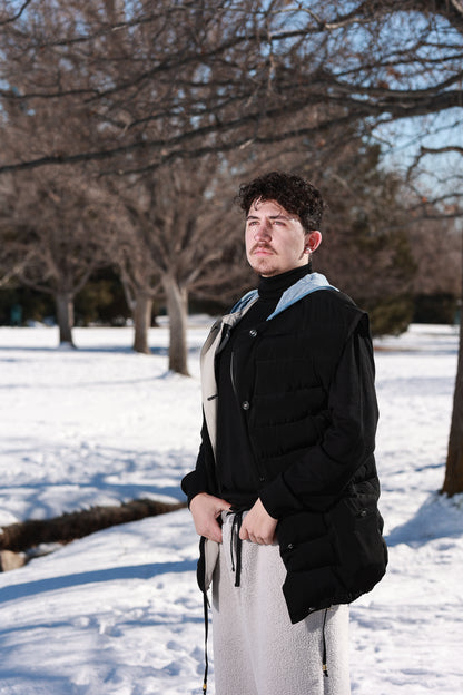 a man standing in the snow wearing a black jacket.