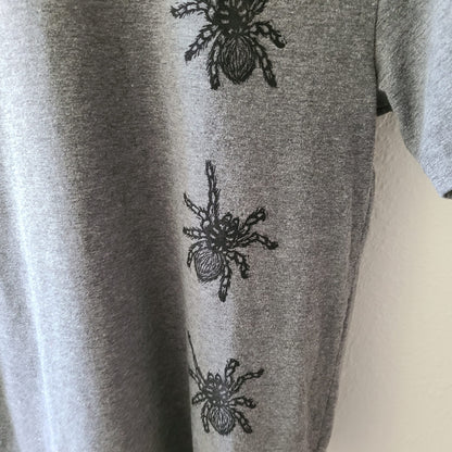 a gray t - shirt with black spiders on it.