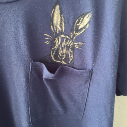 a blue t - shirt with a rabbit on the pocket.