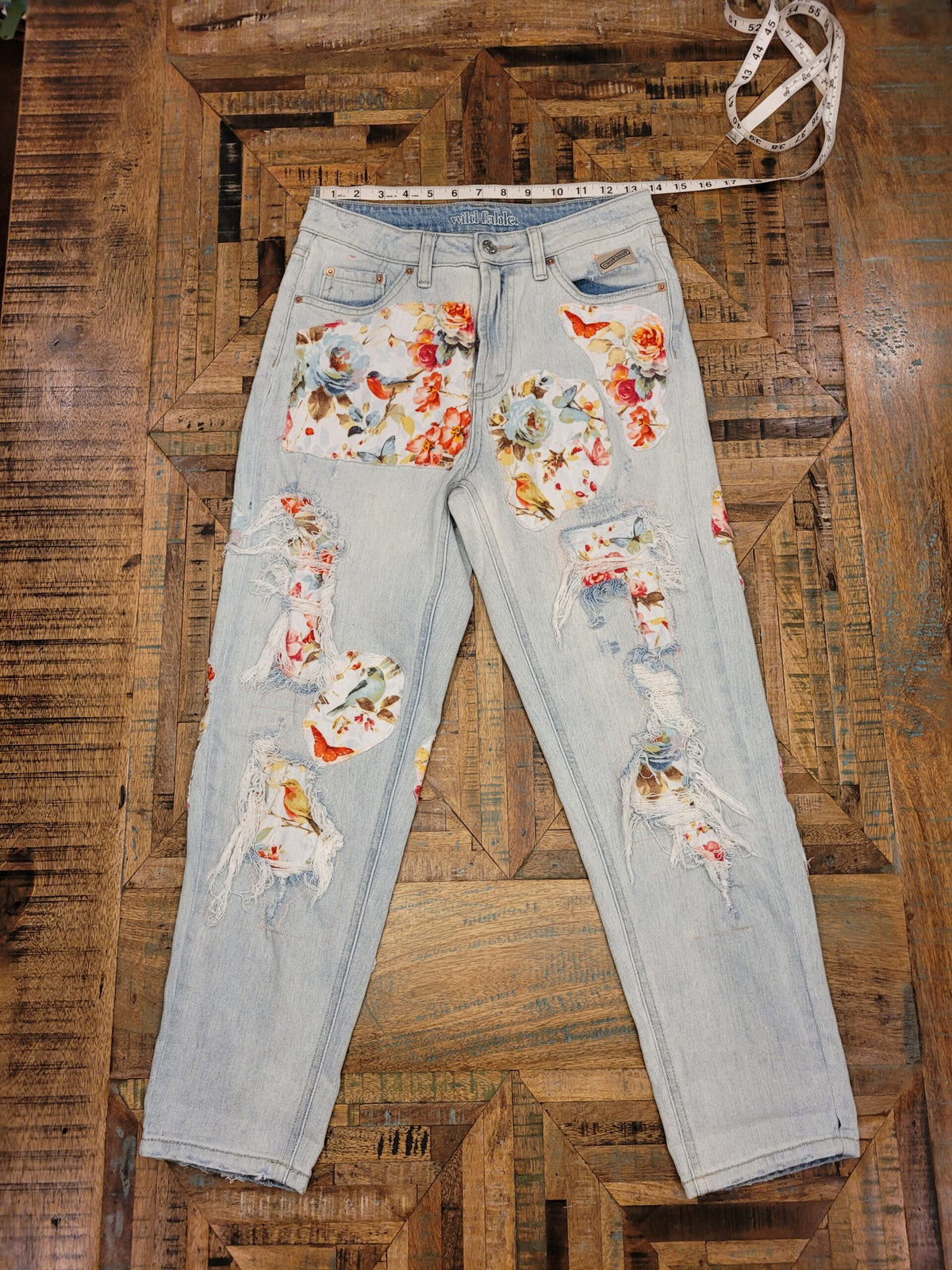 a pair of distressed jeans with flowers on them.