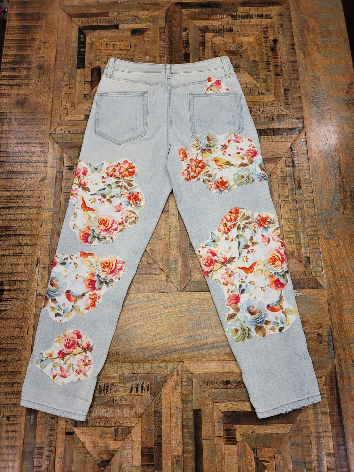 a pair of floral printed jeans on a wooden table.
