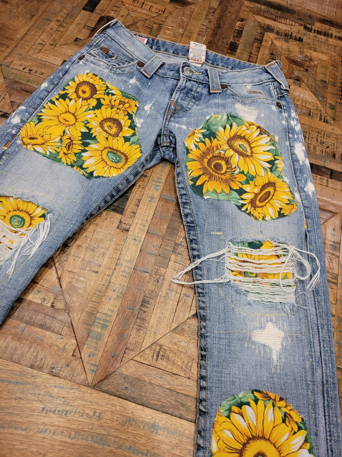 a pair of jeans with sunflowers on them.