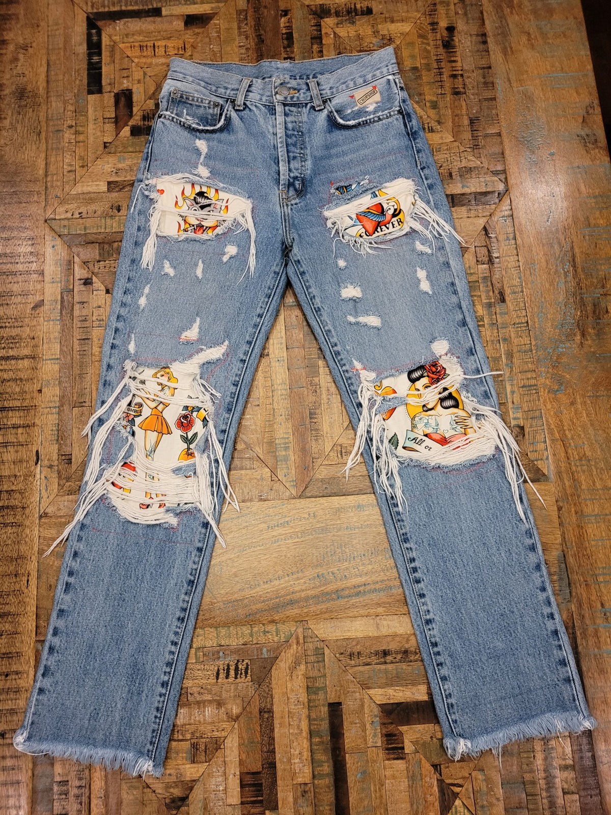 a pair of distressed jeans with patches on them.
