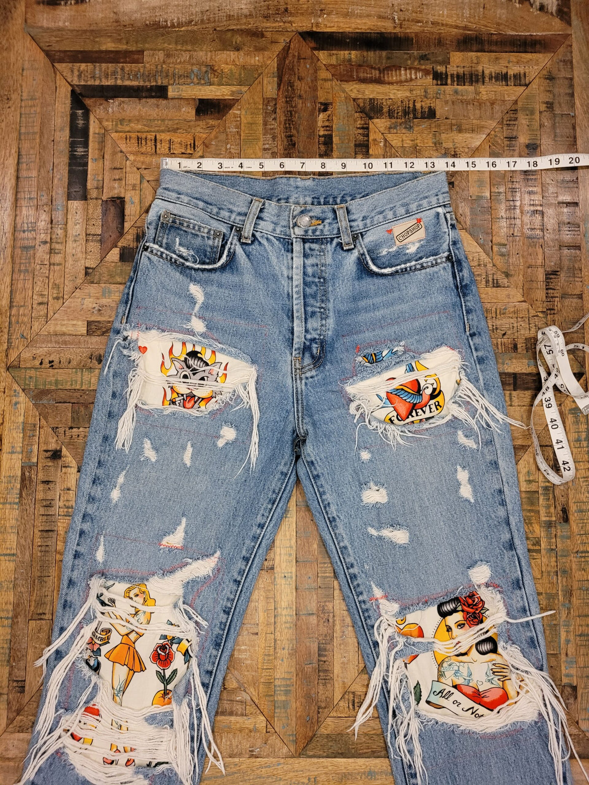 a pair of distressed jeans with patches on them.