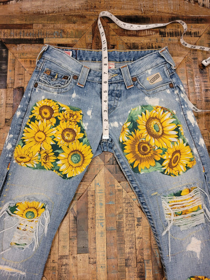 a pair of jeans with sunflowers on them.