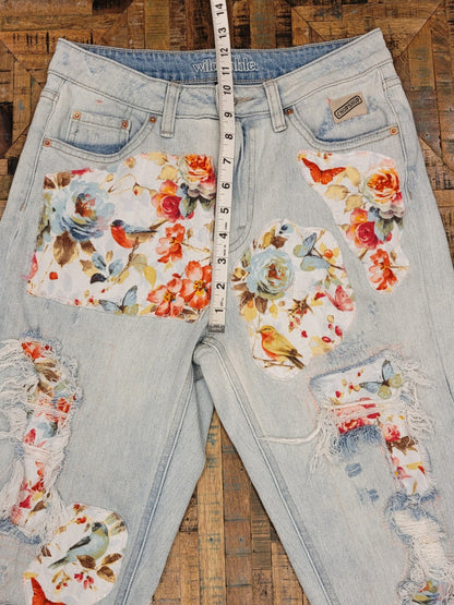 a pair of ripped jeans with flowers on them.