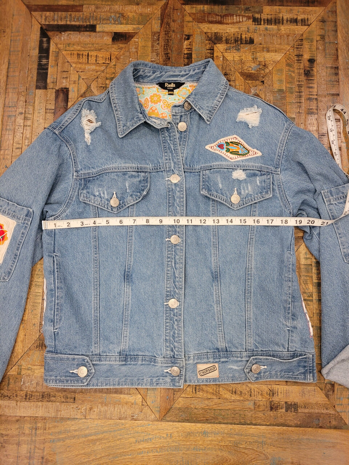a denim jacket with patches and a measuring tape.
