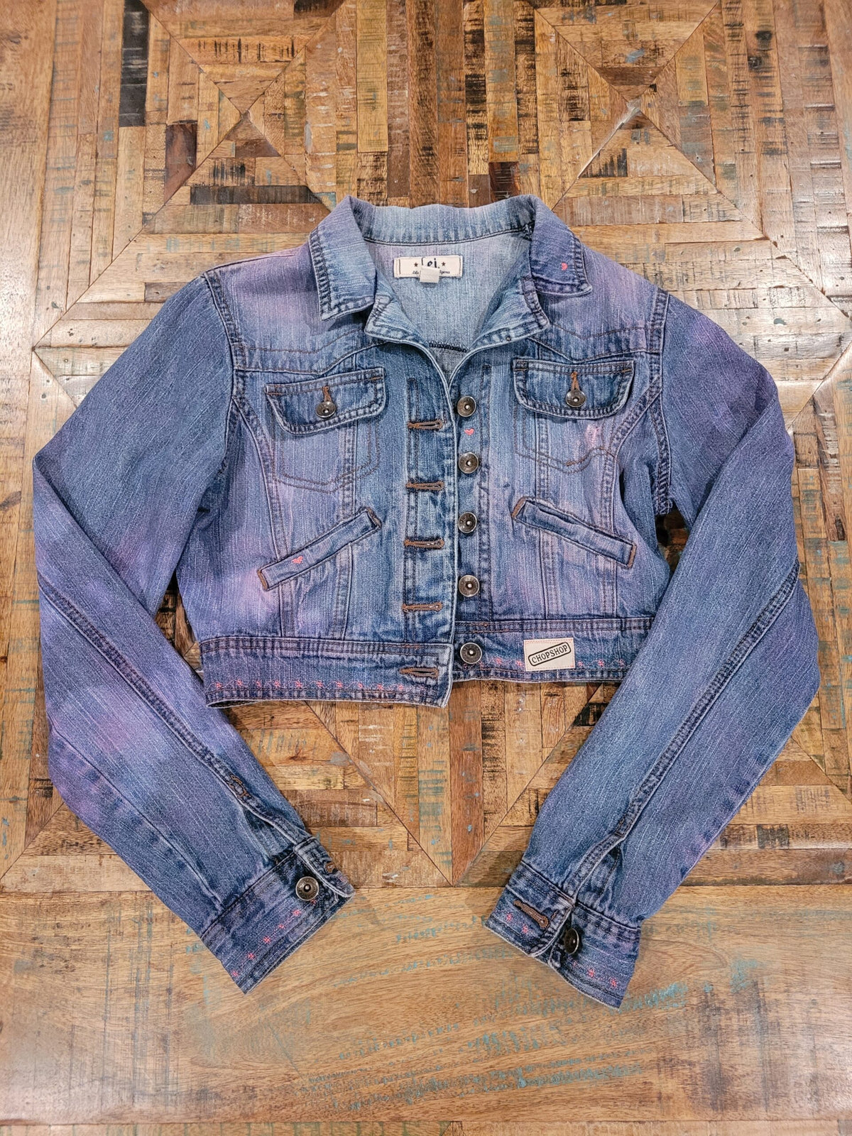a women's denim jacket on a wooden floor.