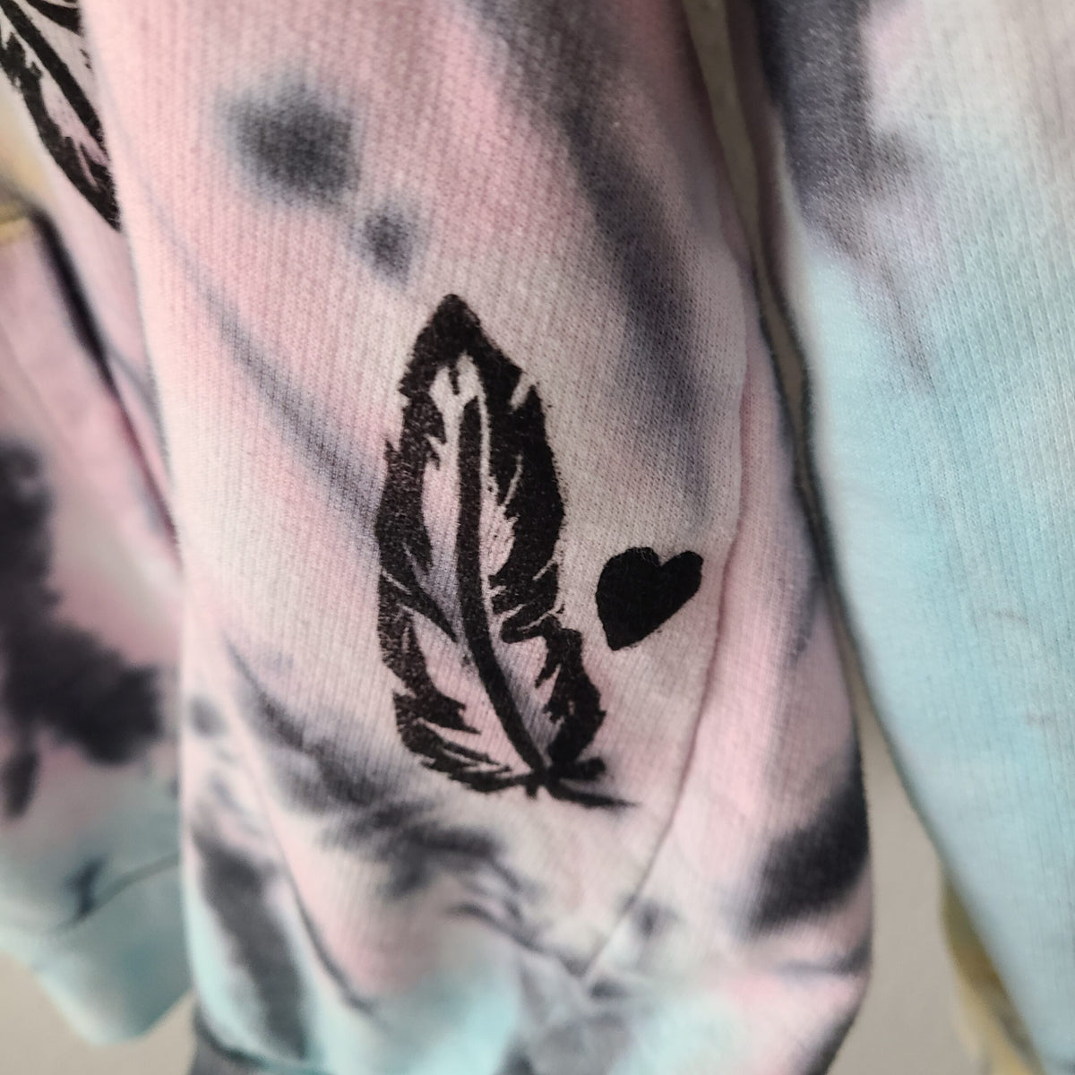 A tie dye hoodie with a feather on it.