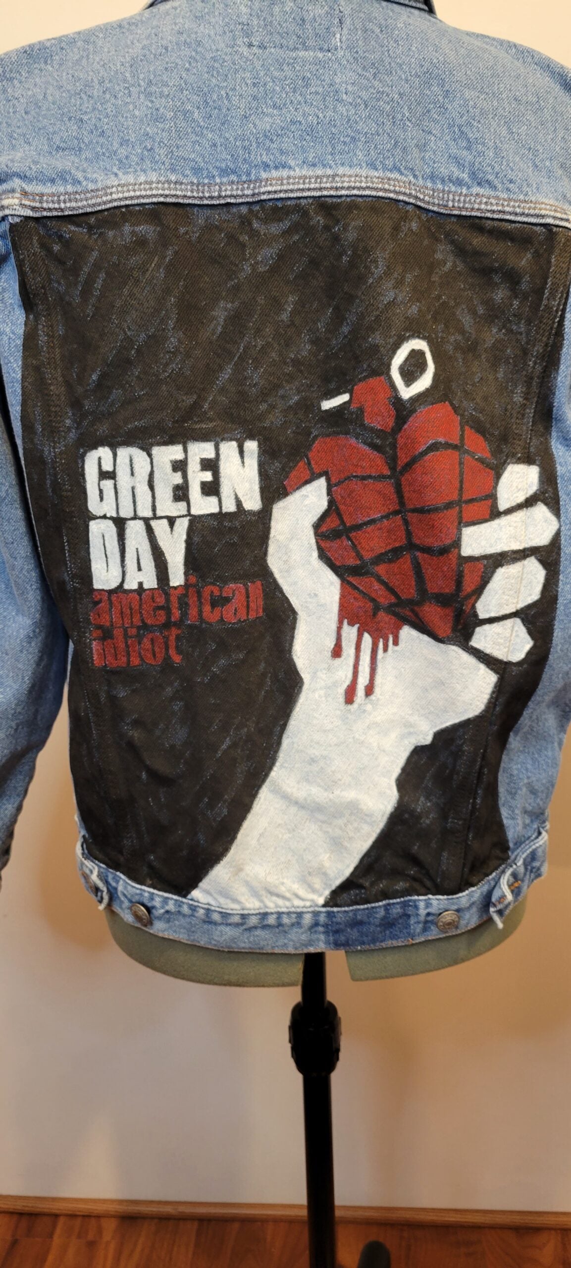 A denim jacket with a hand holding a heart.