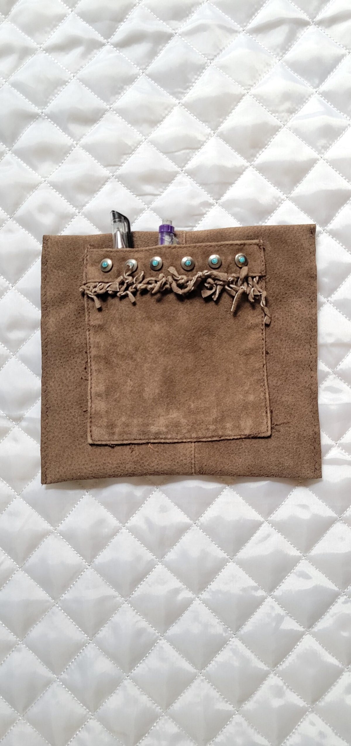 A brown leather pouch with a pen in it.