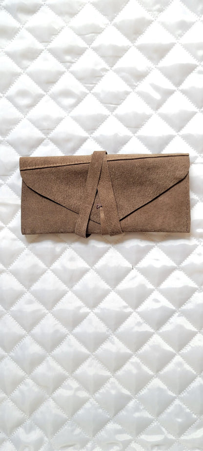 A brown leather pouch on a white quilted surface.