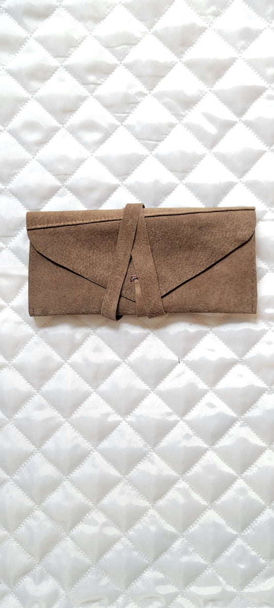 A brown leather pouch on a white quilted surface.