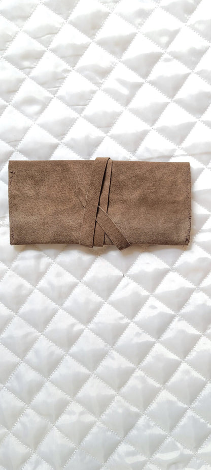 A brown leather pouch on a white quilted surface.