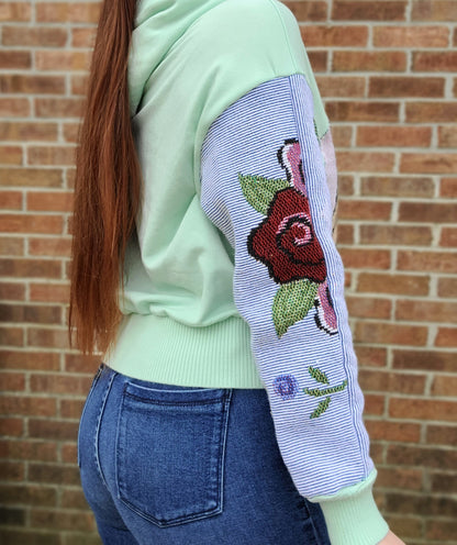 A woman wearing a green and pink embroidered hoodie.
