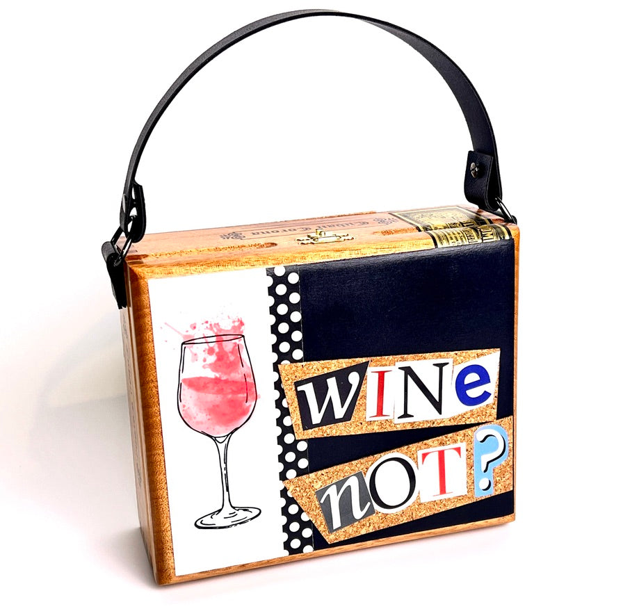 Square wood cigar box purse with drawing of a glass of pink wine and the words "wine not?" spelled out on a black and white background. Black leather handle.