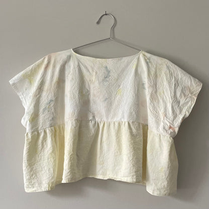 A Yellow Tie-dyed Babydoll Crop Top hanging on a hanger.