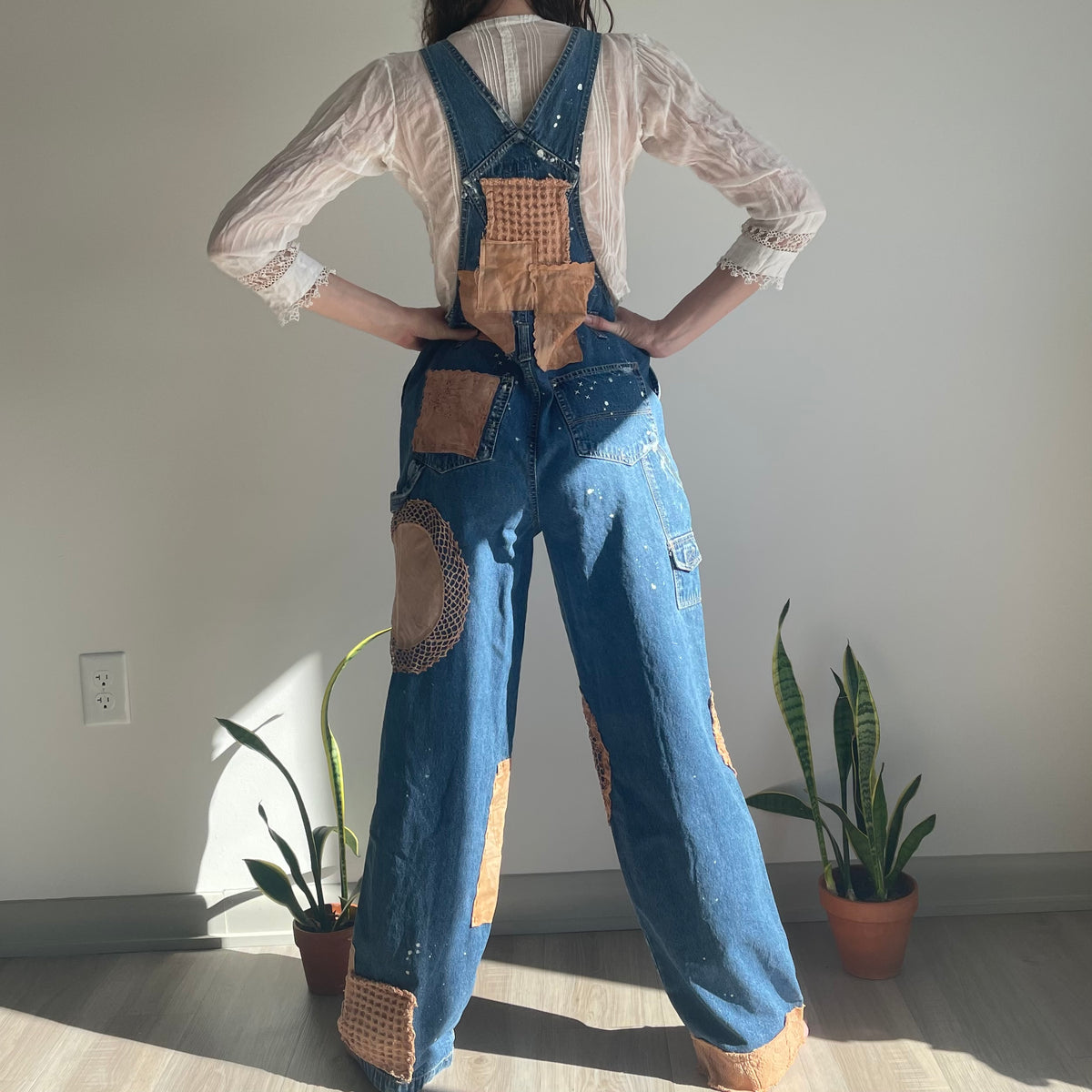 A woman wearing denim overalls with patches.