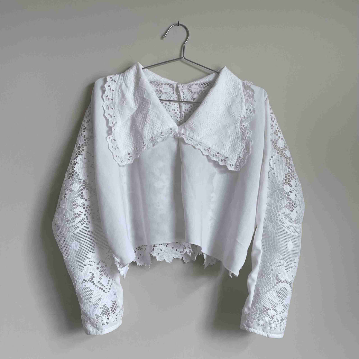 a white blouse hanging on a wall.