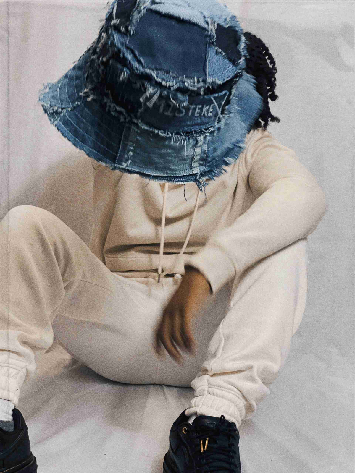 a person sitting on a bed wearing a hat.