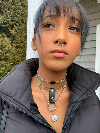 a woman wearing a black jacket with a silver chain around her neck.