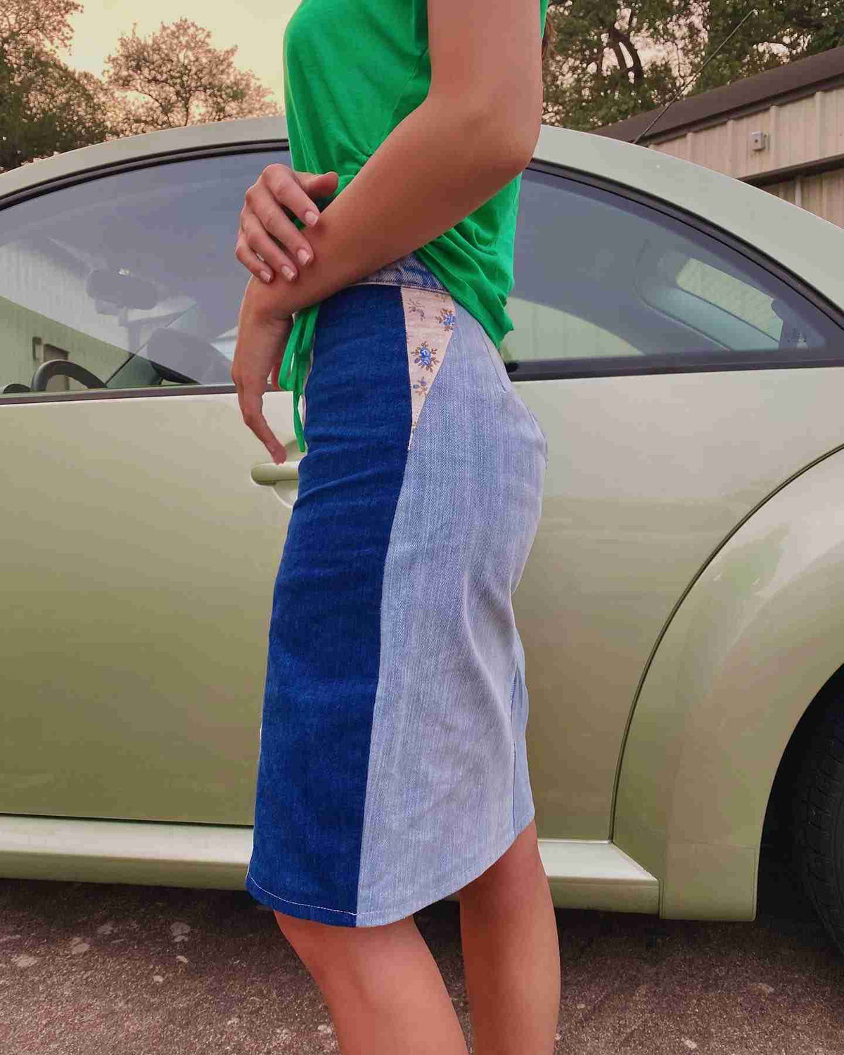 a woman standing in front of a green car.