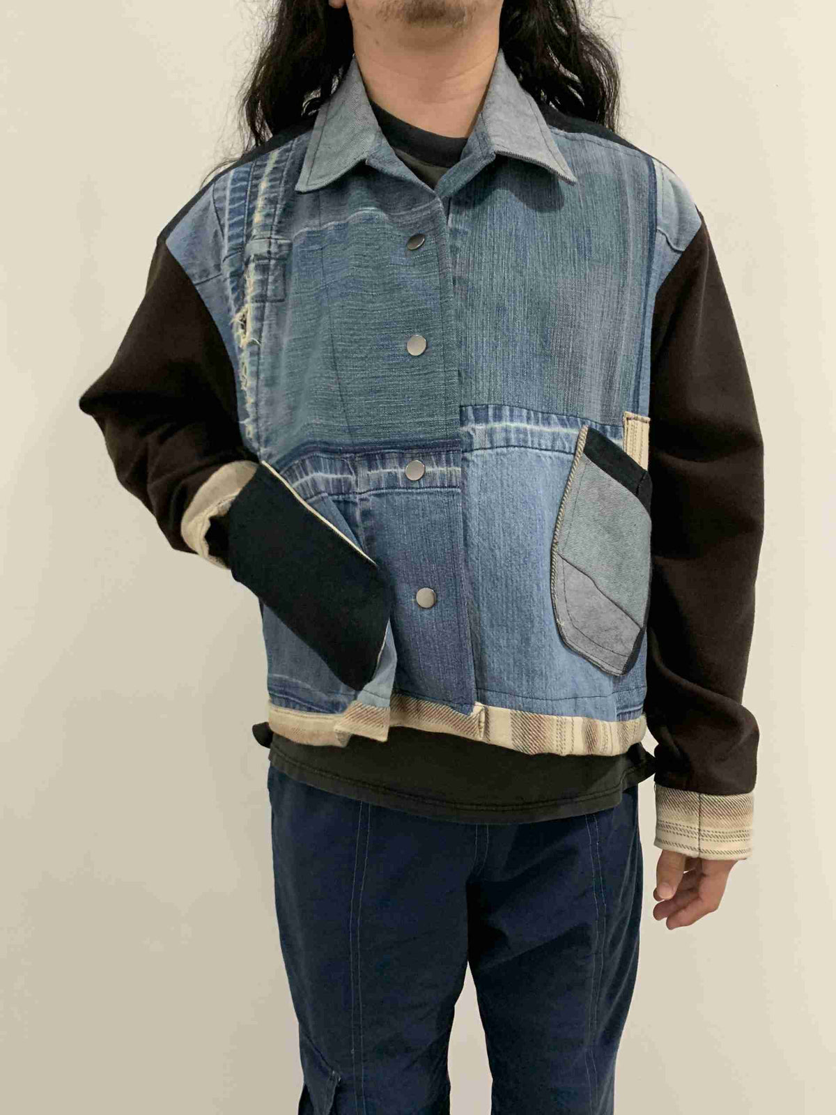 a man with long hair wearing a jean jacket.