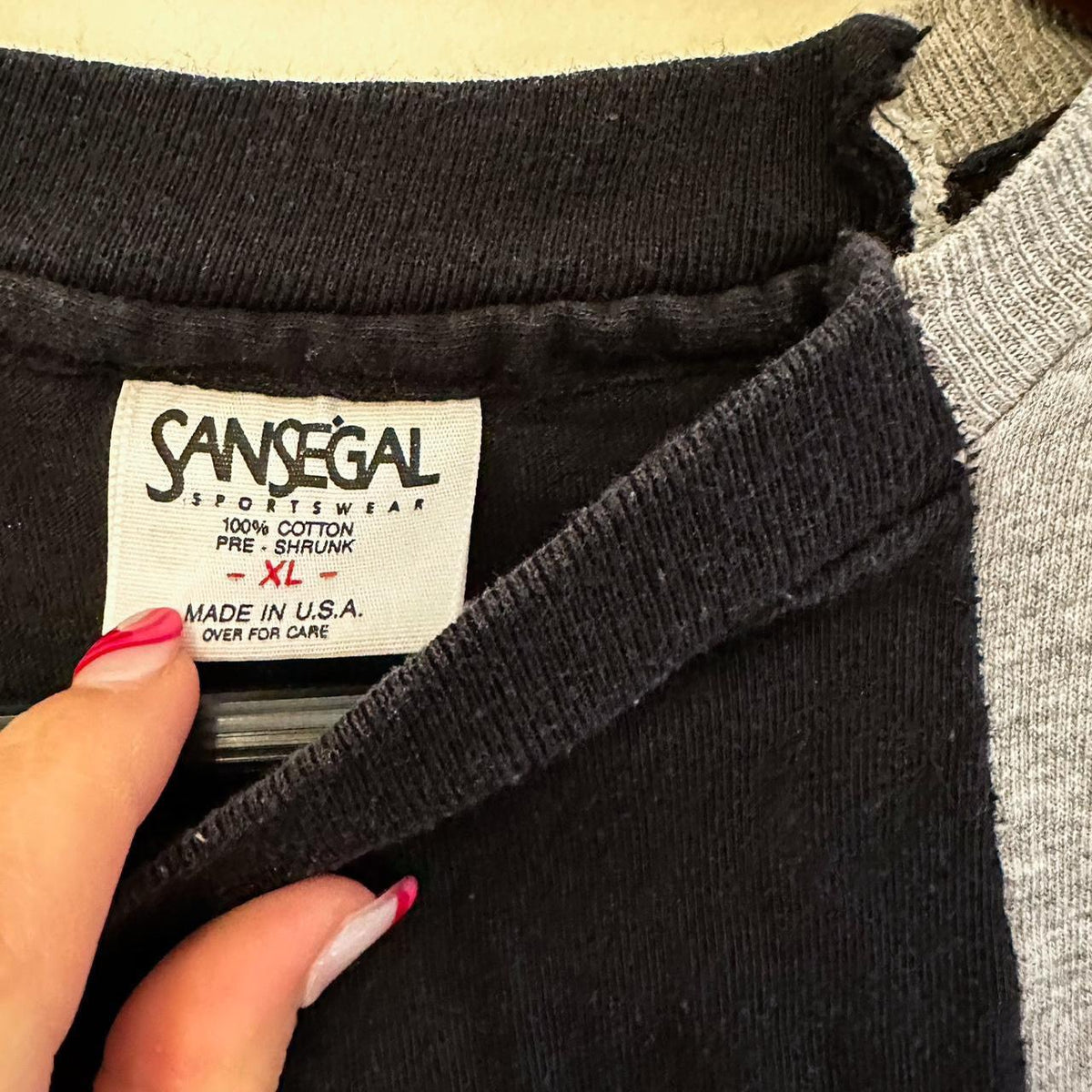 A woman's hand holding a label on a Vintage Nike Reworked Cityscape Skyline Split Tee.