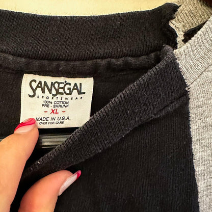 A woman's hand holding a label on a Vintage Nike Reworked Cityscape Skyline Split Tee.