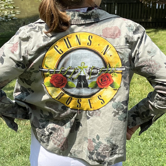 a woman wearing a camouflage jacket with guns and roses on it.