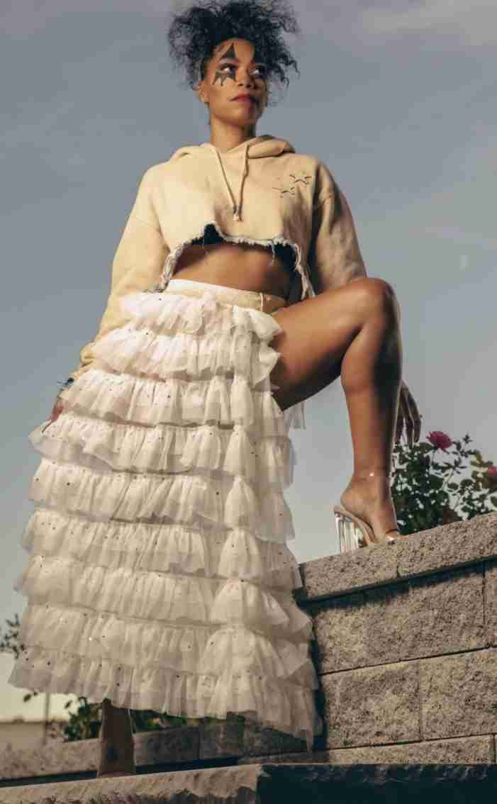 a woman in a skirt sitting on top of a stone wall.