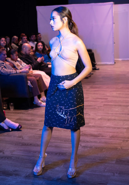 A woman standing on a runway in front of a crowd wearing the Floral fox hand-painted vintage skirt.