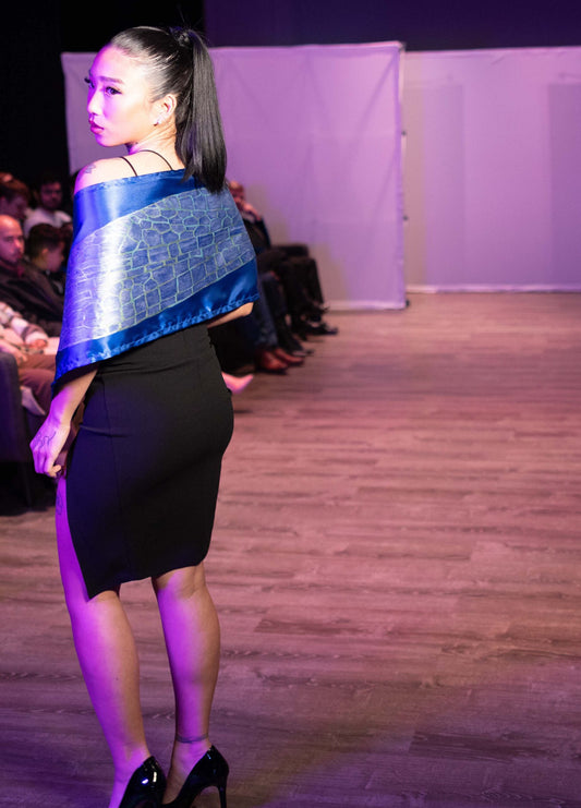 A woman in a black dress and a hand-painted iridescent blue dragonfly wing scarf jacket.