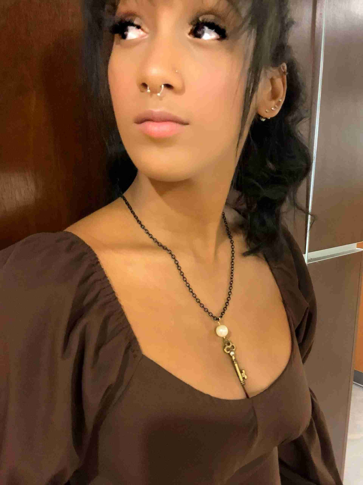 a woman wearing a necklace with a key on it.