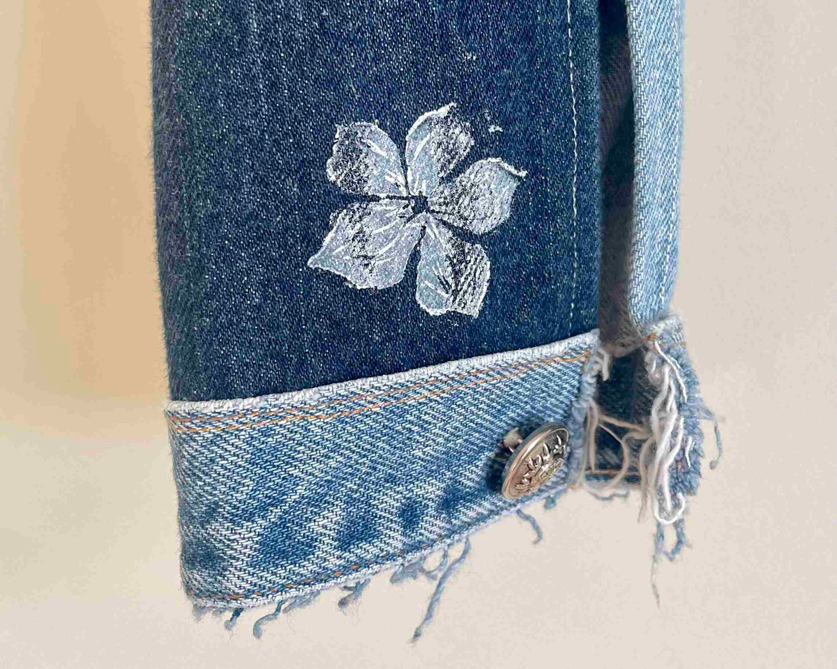 a pair of jeans with a flower embroidered on them.