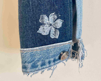 a pair of jeans with a flower embroidered on them.
