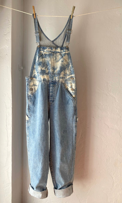 A pair of denim overalls hanging on a clothes line.