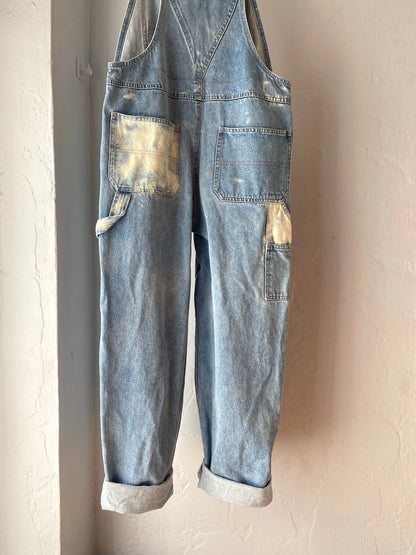 A pair of denim overalls hanging on a wall.