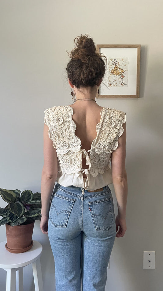 A woman standing in front of a Tea Stained Cream Crochet Festival Tank Top w/ Tie Back.