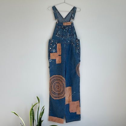 A pair of denim overalls hanging on a wall.
